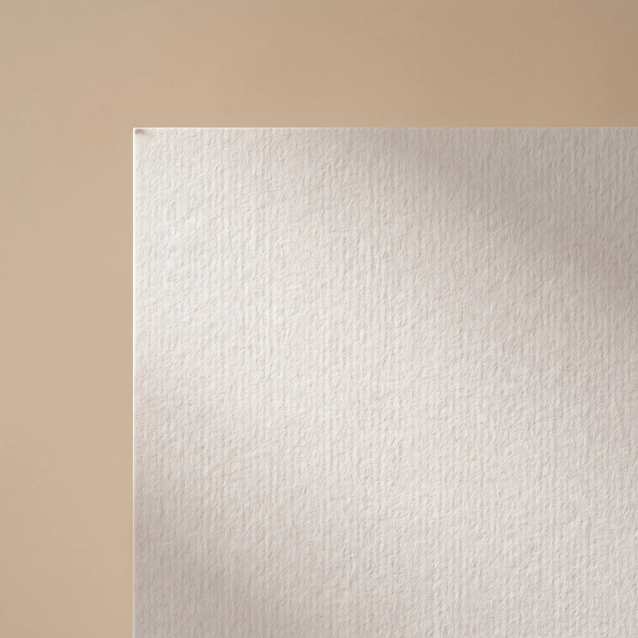 Détail de matière d'une série ambiance bureau : feuille de papier à grain épais sur fond beige, lumière douce qui révèle le relief