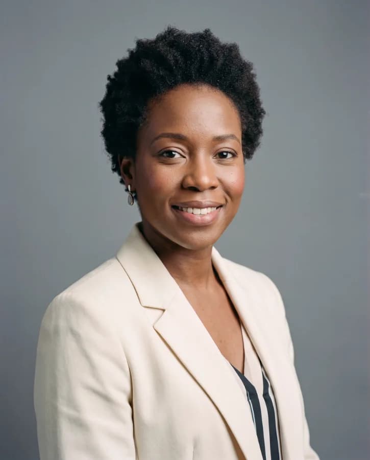 Portrait corporate d’une femme d’une trentaine d’années, blazer crème, boucles d’oreilles discrètes, fond gris studio (démonstration, personne fictive)